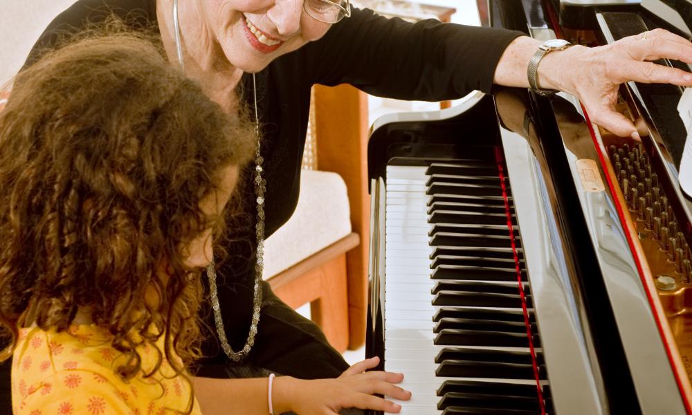 Older lady teaching child piano