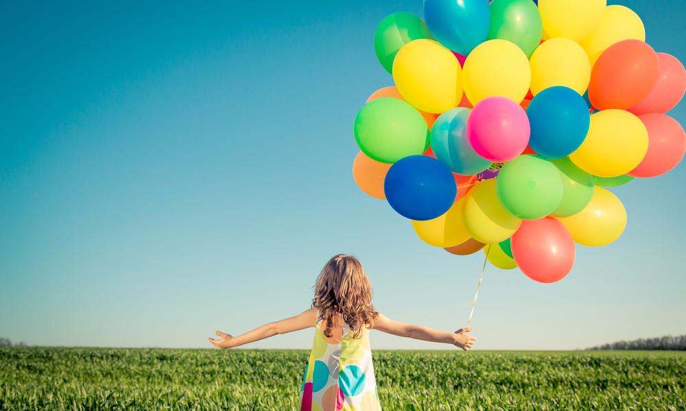 Child in field with balloons